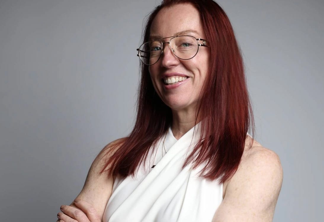 Dr. Betsy Grunch smiling and standing with both arms crossed in white jumpsuit
