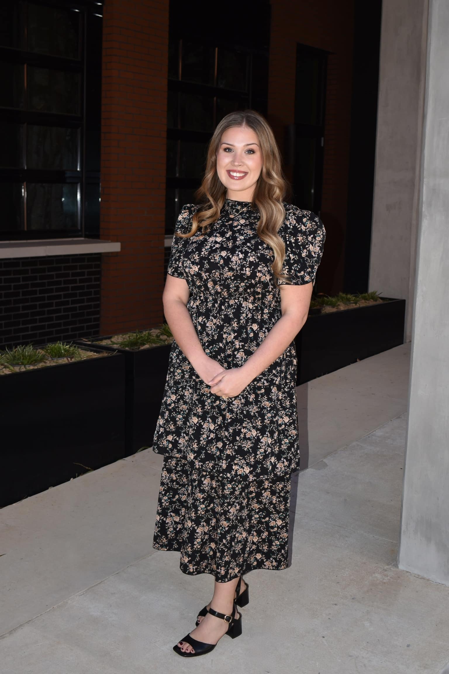 Southern Neurosurgery team member standing outside wearing black floral dress